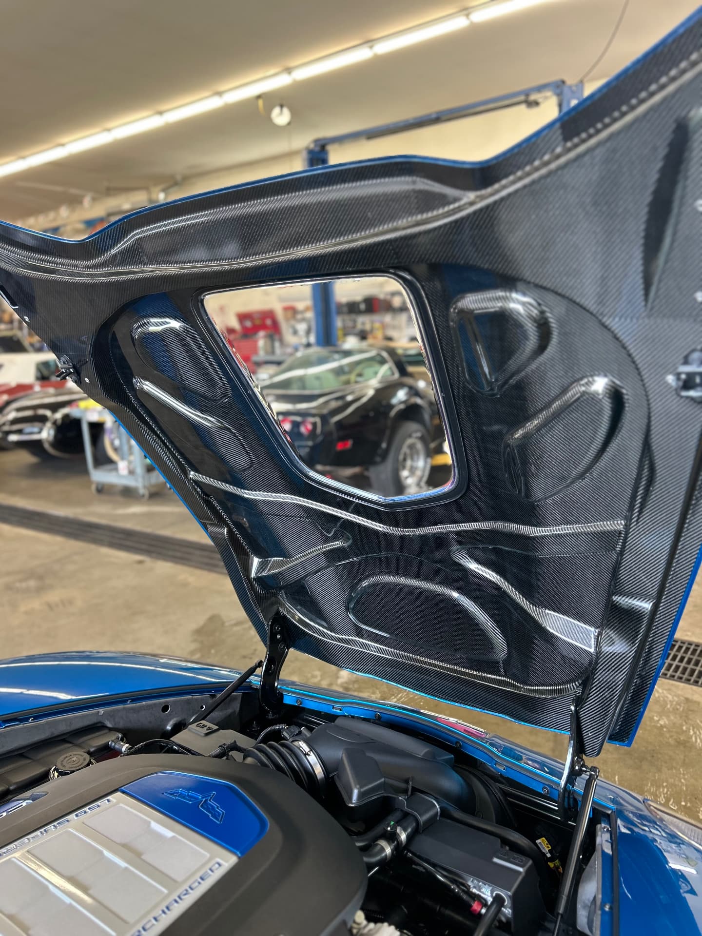 Open Corvette hood and engine bay with reflective painted surfaces